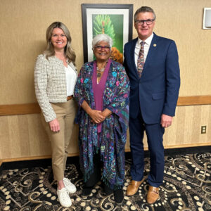 The Honourable Jill Dunlop, Dr. Sarita Verma, and MPP Kevin Holland stand together for a photo. Dunlop wears a light woven jacket and khakis; Dr. Verma wears a dark floral shawl; and Holland wears a navy suit.
